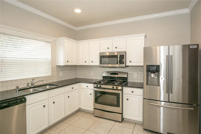 a kitchen with white cabinets white stainless steel appliances and sink