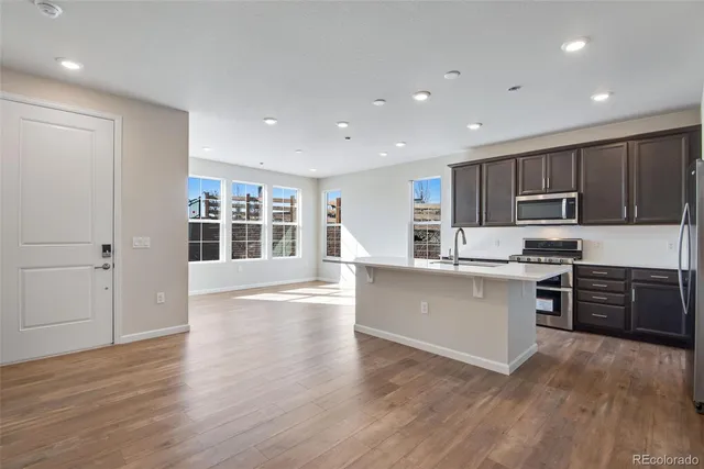 a open kitchen with kitchen island a sink wooden floor and a refrigerator