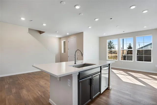 a open kitchen with kitchen island a sink appliances and a large window