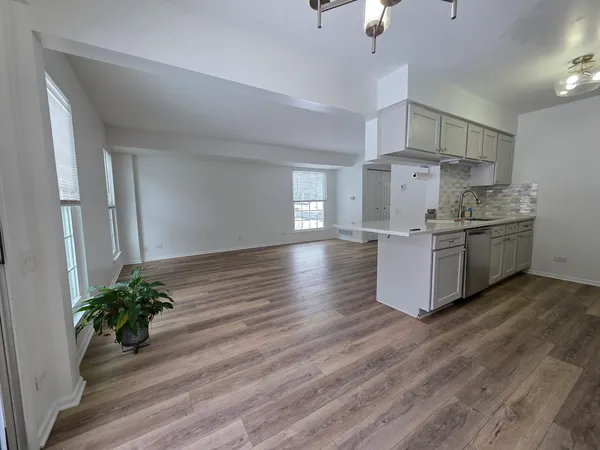 a room with kitchen island stainless steel appliances a stove and wooden floor