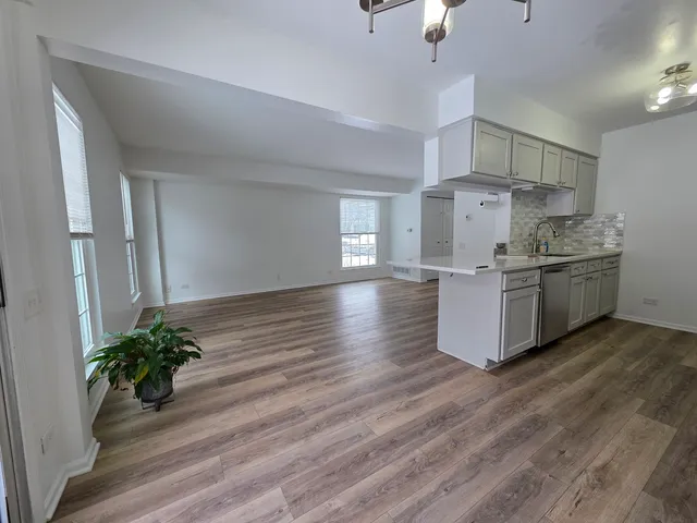 a room with kitchen island stainless steel appliances a stove and wooden floor