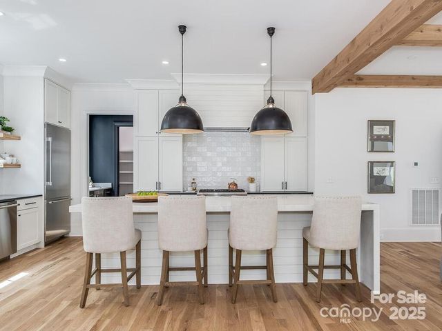 a kitchen with stainless steel appliances a dining table chairs and wooden floor