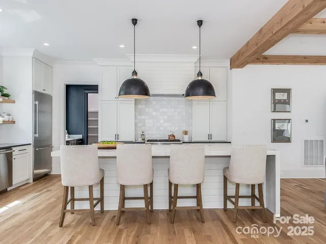 a kitchen with stainless steel appliances a dining table chairs and wooden floor