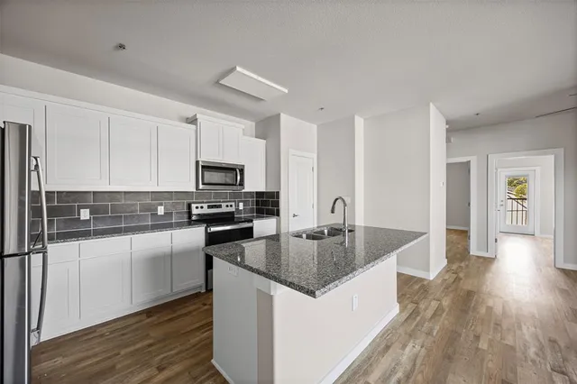 a kitchen with stainless steel appliances granite countertop a stove top oven a sink and a refrigerator