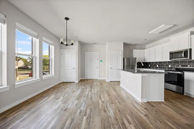 a view of kitchen with granite countertop stainless steel appliances sink and cabinets