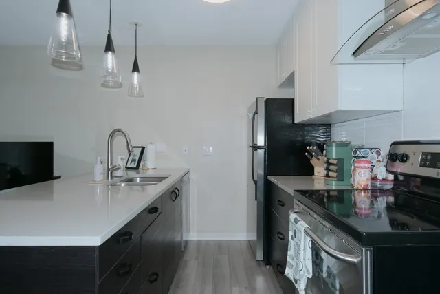 a kitchen with stainless steel appliances granite countertop a sink a stove and a refrigerator