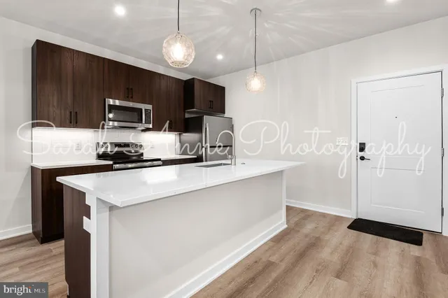 a kitchen with kitchen island a counter space a sink appliances and cabinets
