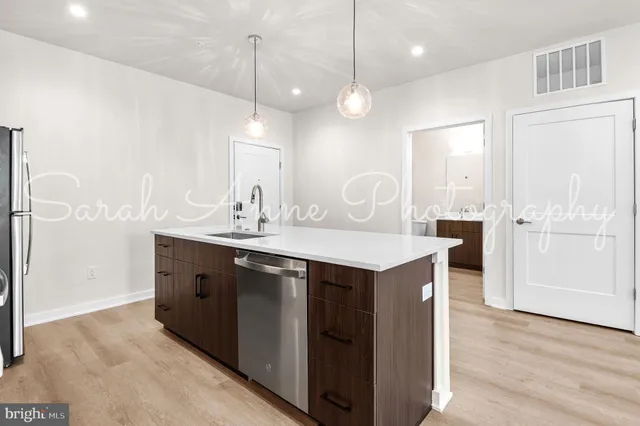 a kitchen with kitchen island a sink stainless steel appliances and wooden floor