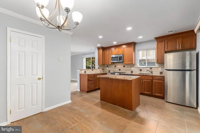 a large kitchen with stainless steel appliances granite countertop a stove a sink dishwasher a refrigerator and a dining table with wooden floor