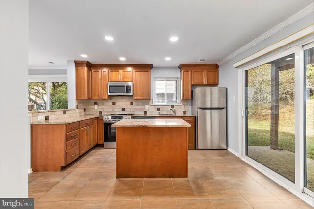 a kitchen with stainless steel appliances granite countertop a stove top oven a sink dishwasher a refrigerator and a microwave