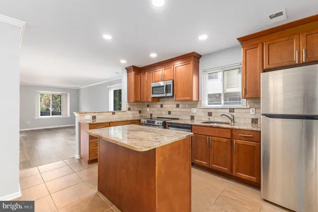 a kitchen with stainless steel appliances granite countertop wooden cabinets stove top oven and sink
