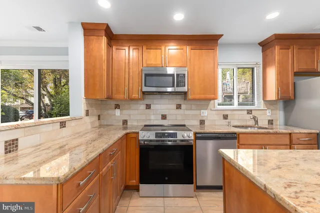 a kitchen with stainless steel appliances granite countertop a stove a sink dishwasher a refrigerator and a microwave oven with wooden cabinets