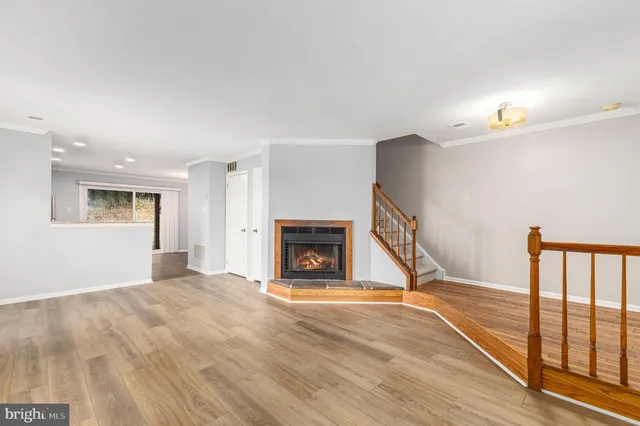 a view of an empty room with wooden floor fireplace and a window