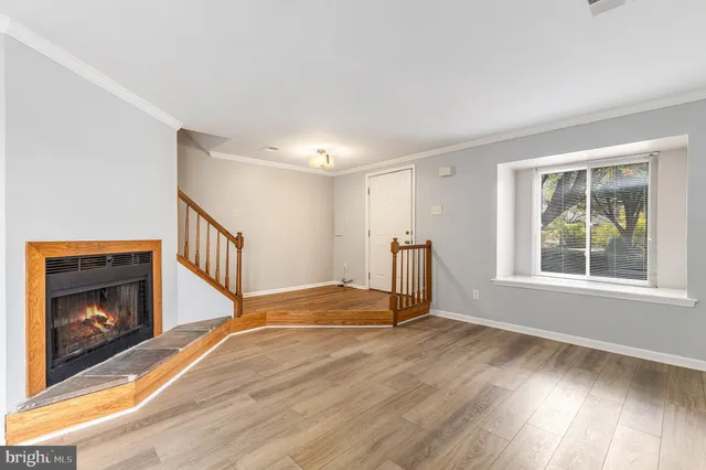 a view of an empty room with wooden floor fireplace and a window