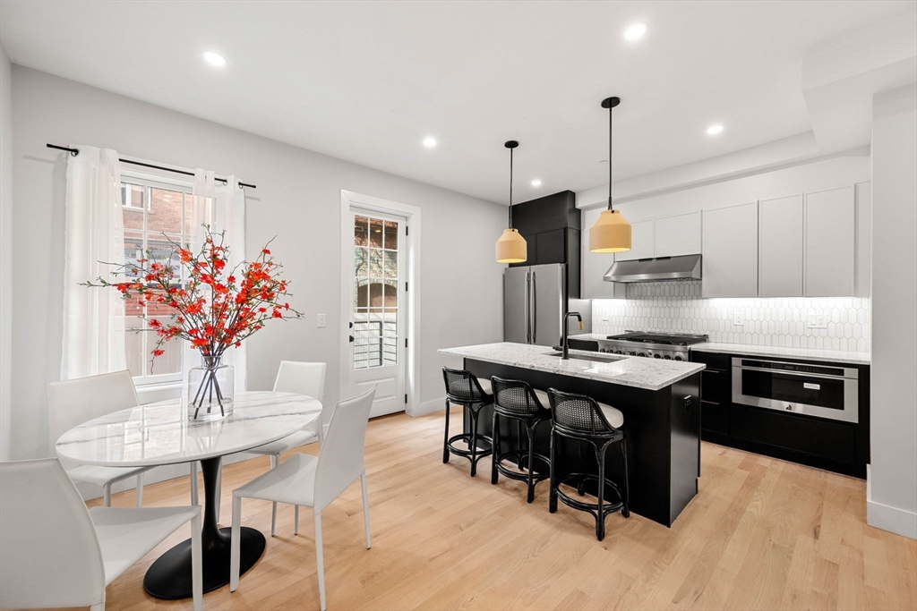 67 Revere Street, Unit 1 Boston, MA 02114 - Photo 3 of 29 a kitchen with stainless steel appliances granite countertop a stove a sink dishwasher a dining table and chairs with wooden floor