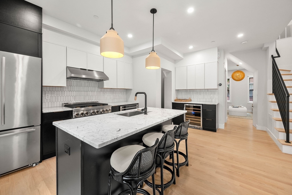 67 Revere Street, Unit 1 Boston, MA 02114 - Photo 4 of 29 a kitchen with stainless steel appliances granite countertop a sink a stove a refrigerator and island with wooden floor