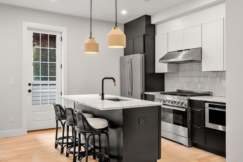 67 Revere Street, Unit 1 Boston, MA 02114 - Photo 5 of 29 a kitchen with stainless steel appliances granite countertop a stove a sink and a refrigerator