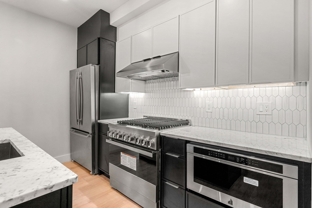 67 Revere Street, Unit 1 Boston, MA 02114 - Photo 6 of 29 a kitchen with stainless steel appliances granite countertop a stove a refrigerator and a microwave