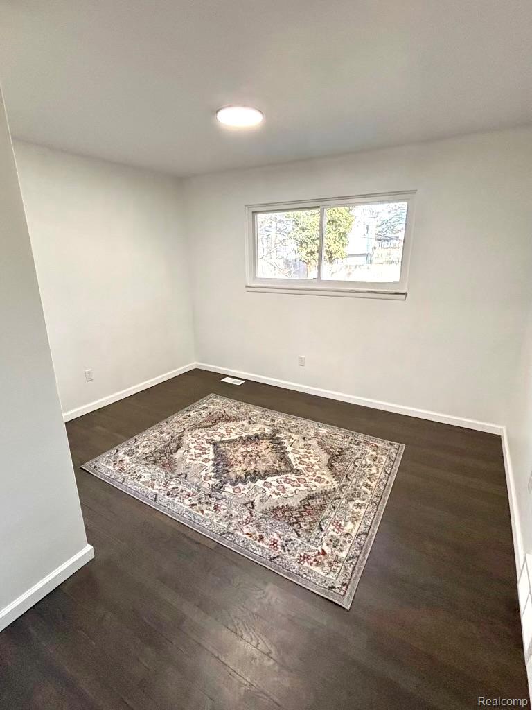 24065 Rockingham Street Southfield, MI 48033 - Photo 26 of 35 Empty room featuring dark wood-style flooring and baseboards