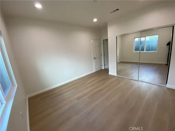 an empty room with wooden floor and mirror