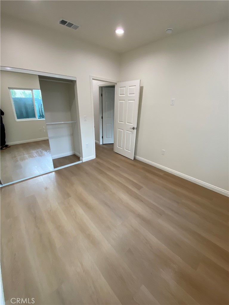18543 Ingomar Street Reseda, CA 91335 - Photo 8 of 10 an empty room with wooden floor and mirror