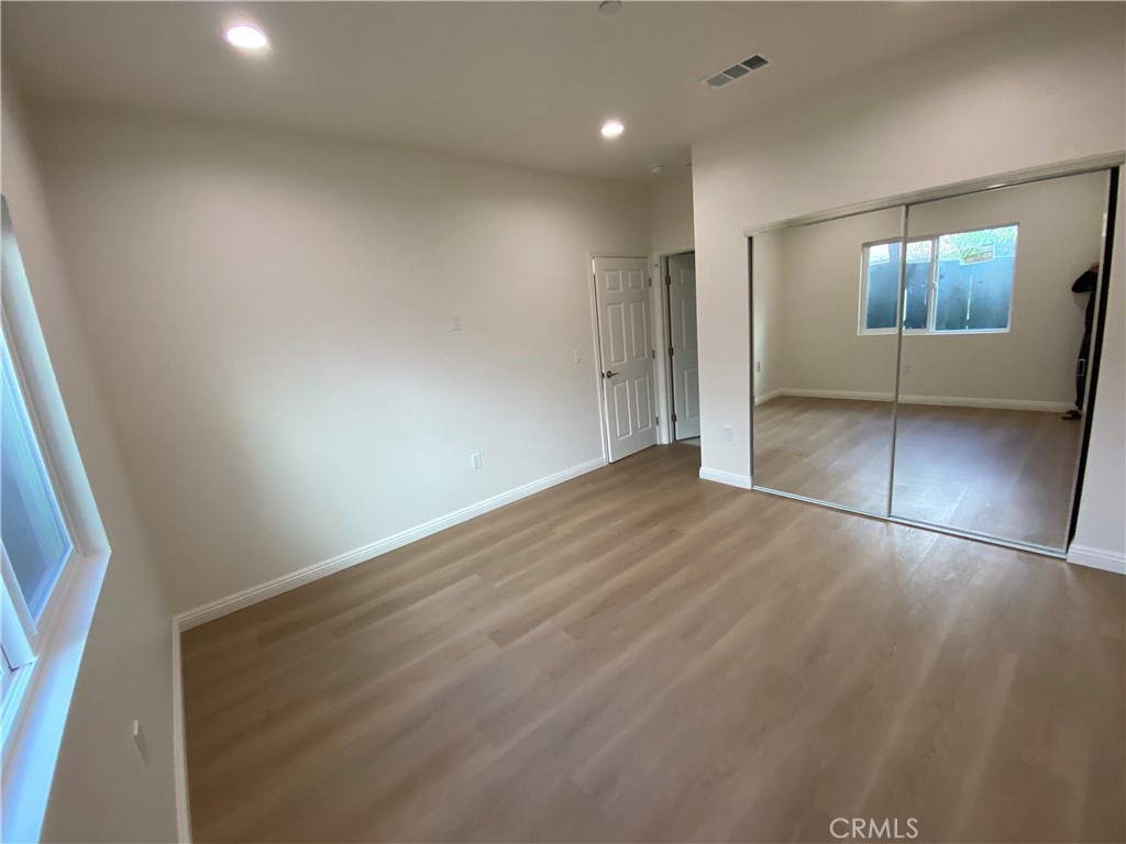 18543 Ingomar Street Reseda, CA 91335 - Photo 9 of 10 an empty room with wooden floor and mirror
