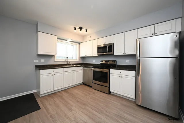 a kitchen with granite countertop white cabinets and white appliances
