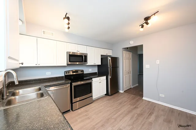 a kitchen with stainless steel appliances granite countertop a sink a stove a refrigerator and a microwave