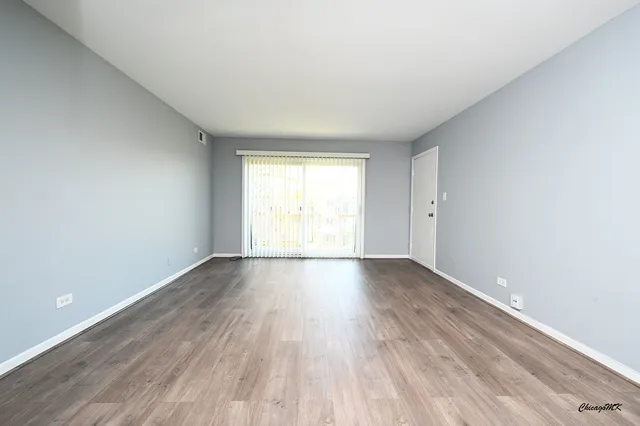 a view of an empty room and wooden floor and window