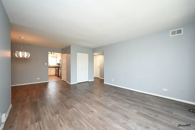 a view of an empty room with window and wooden floor