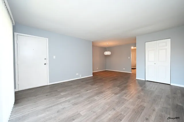 an empty room with wooden floor & windows