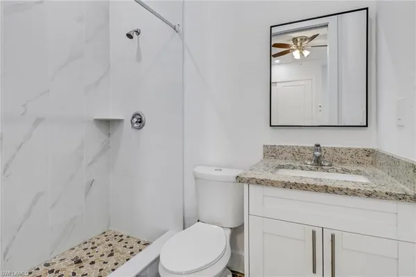 a bathroom with a granite countertop sink toilet and shower