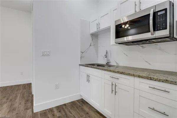 a kitchen with granite countertop white cabinets and microwave