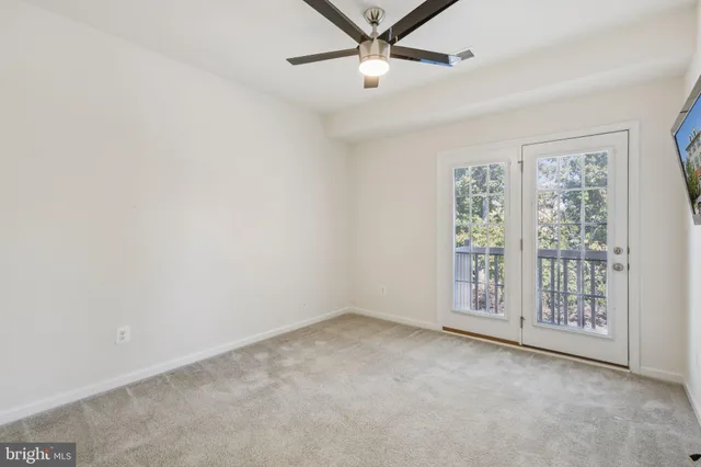 an empty room with windows and ceiling fan