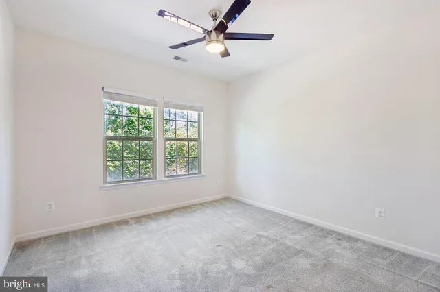 an empty room with a window and a fan