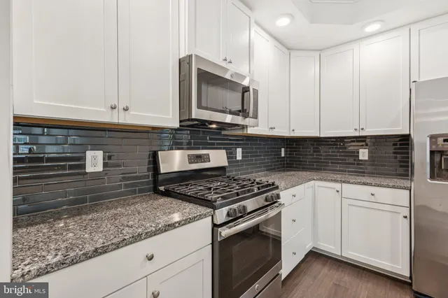 a kitchen with granite countertop white cabinets stainless steel appliances and a sink