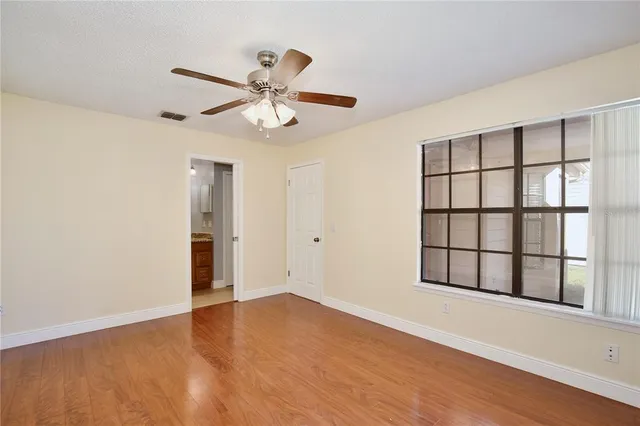 a view of an empty room with a window and wooden floor