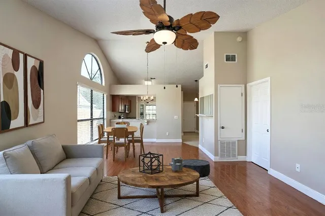 a living room with couches chairs and kitchen view with wooden floor
