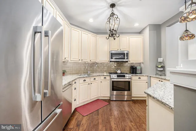 a kitchen with stainless steel appliances granite countertop a refrigerator a stove top oven a sink and dishwasher