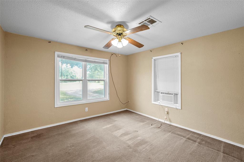 4704 Williams Road Bellmead, TX 76705 - Photo 20 of 32 Neutral tone walls featuring two distinct windows, brown carpet, and a ceiling fan with light fixture