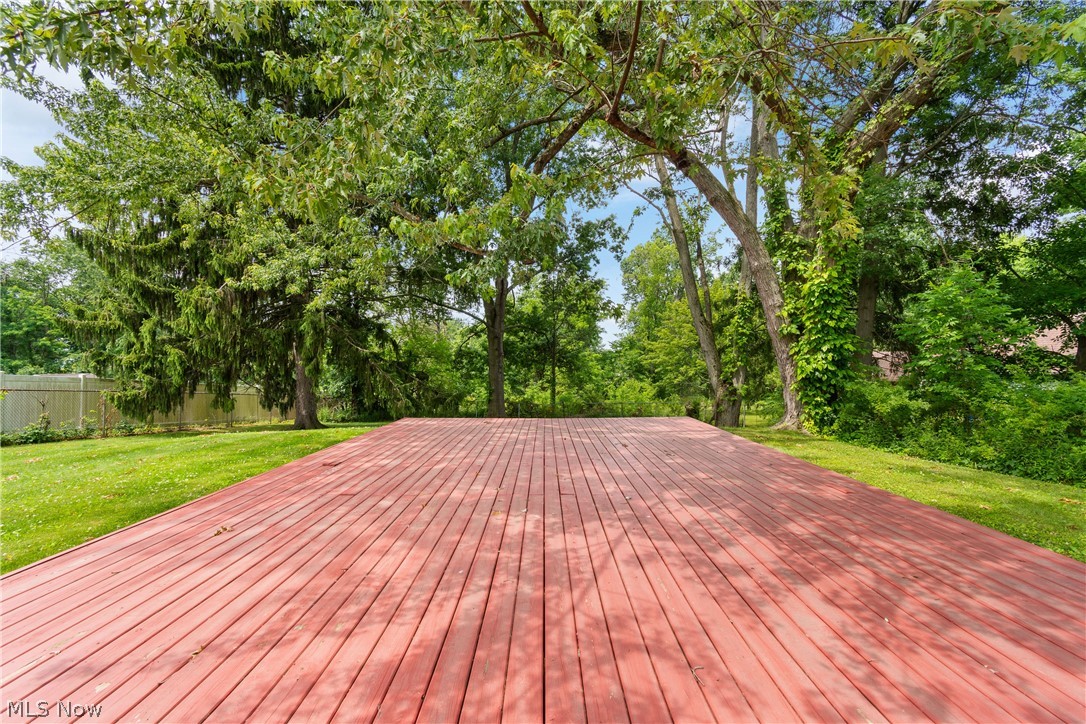 5768 Nolley Road Akron, OH 44319 - Photo 25 of 38 Expansive red-toned wood deck surrounded by mature trees and a manicured lawn