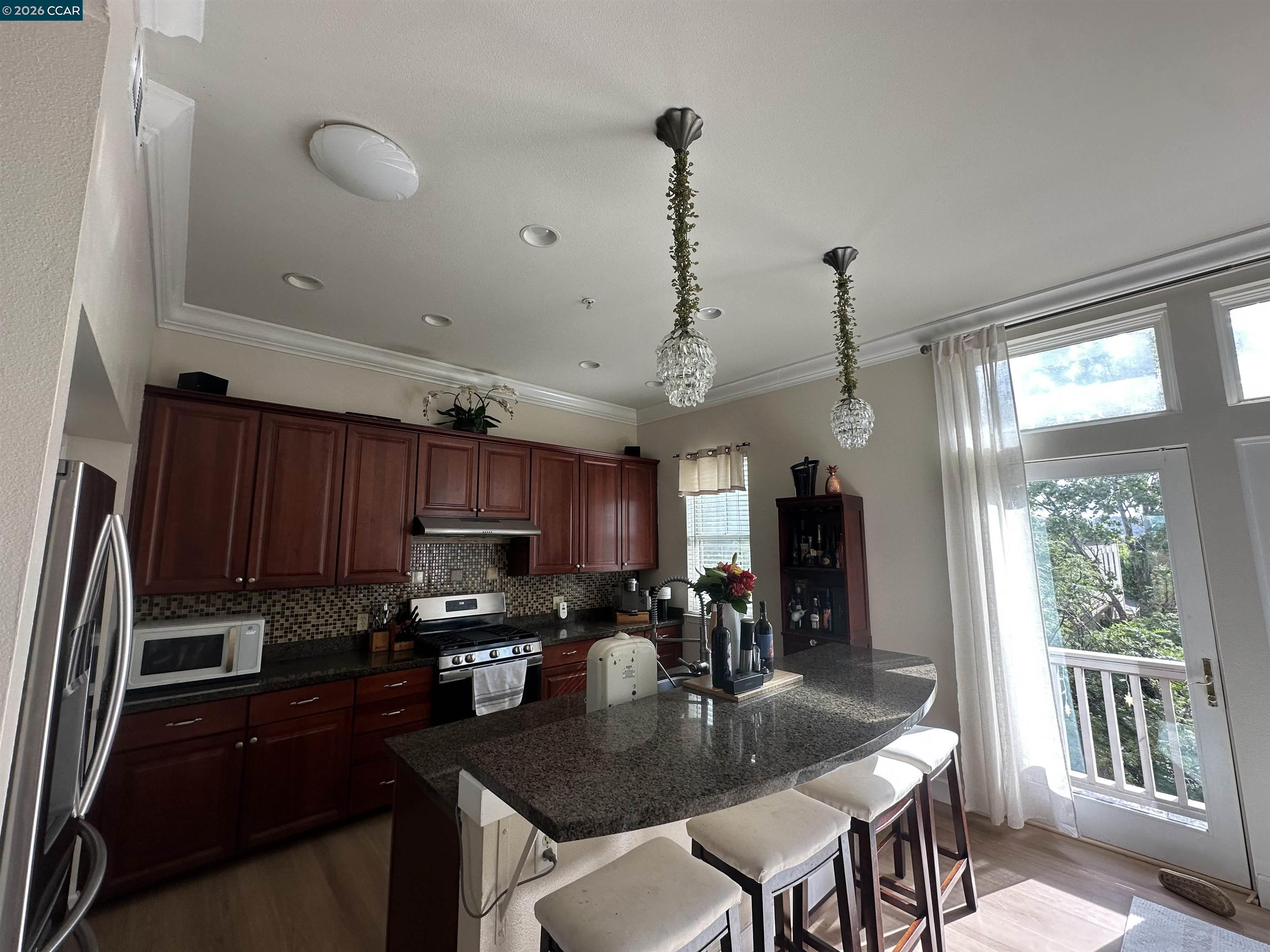 2144 Railroad Avenue Hercules, CA 94547 - Photo 20 of 29 a kitchen with granite countertop stainless steel appliances a stove a refrigerator a sink a dining table and chairs with wooden floor