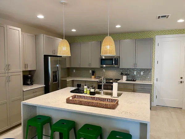 a kitchen with kitchen island granite countertop a sink a stove and refrigerator