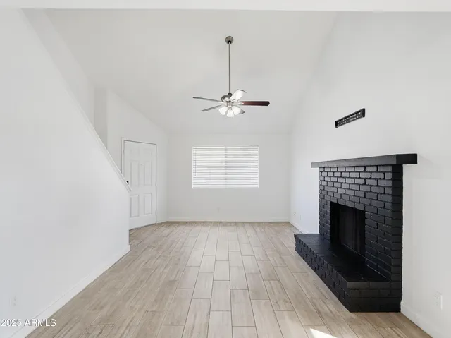 a view of a livingroom with wooden floor a fireplace and a window