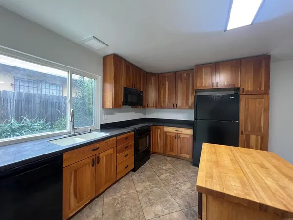 a kitchen with granite countertop wooden cabinets a refrigerator and a sink