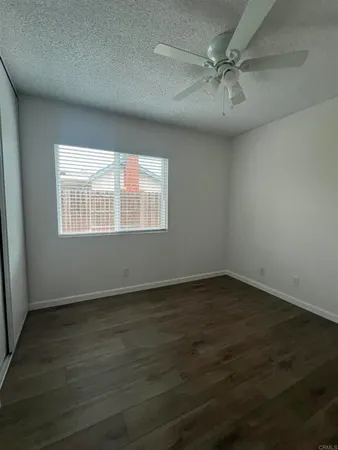 an empty room with wooden floor fan and windows