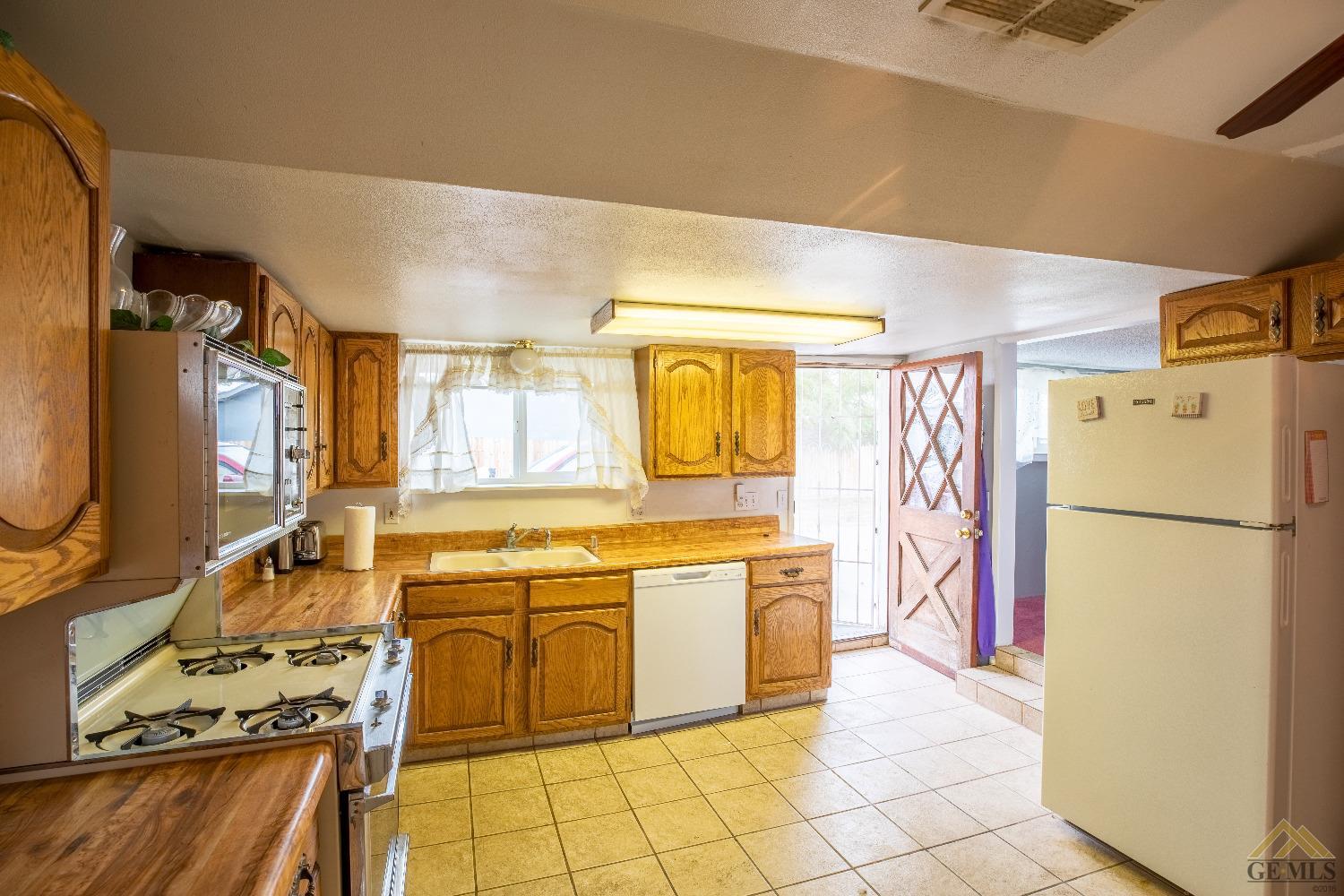 Undisclosed Address Taft, CA 93268 - Photo 9 of 24 a kitchen with a refrigerator a stove a sink and a dining table with wooden floor