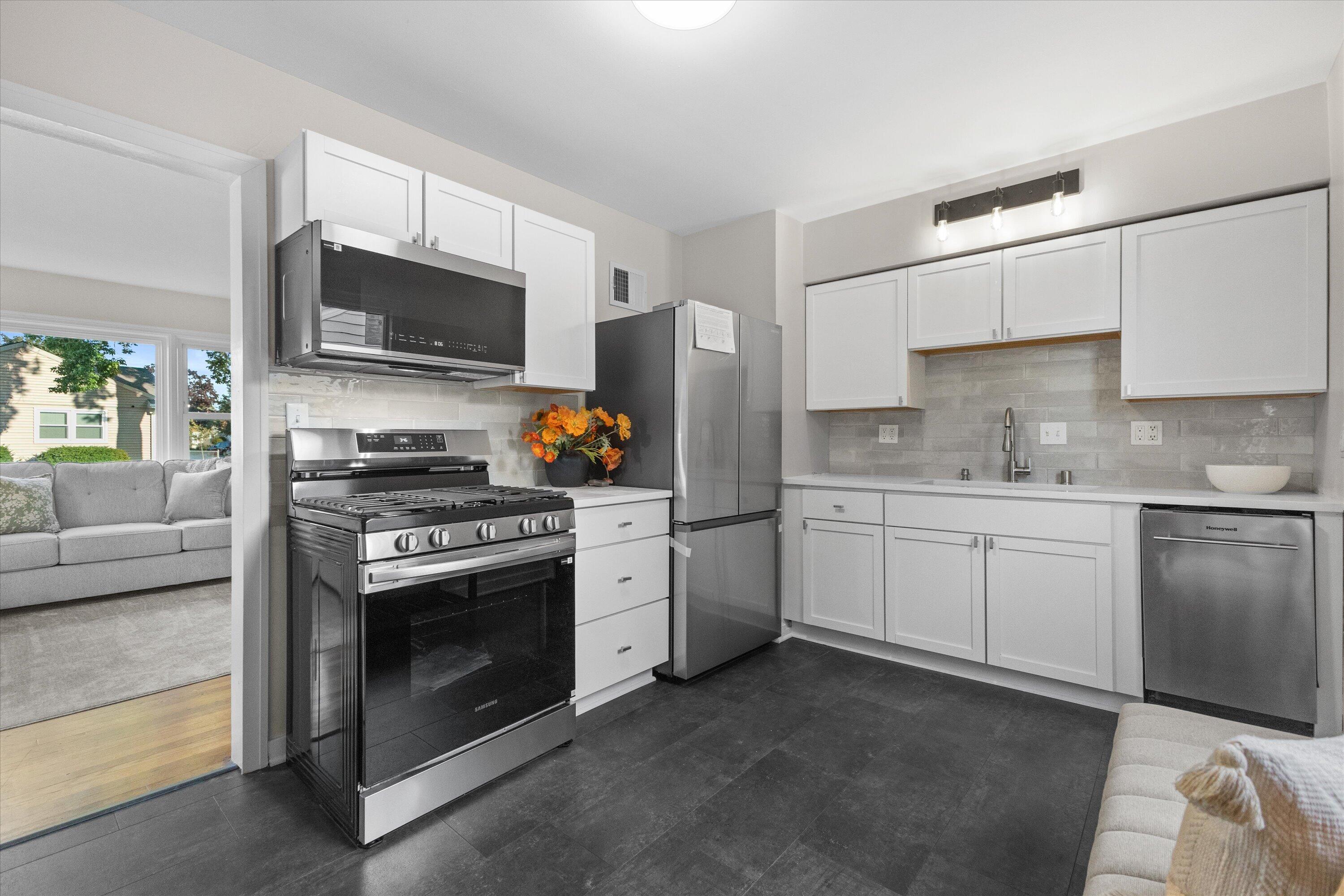 1905 Gilson Street Racine, WI 53403 - Photo 4 of 13 Newly updated kitchen features crisp white cabinetry, quartz countertops, tile backsplash and new stainless steel appliances.