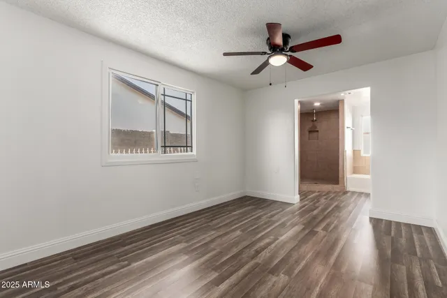 a view of empty room with wooden floor and ceiling fan