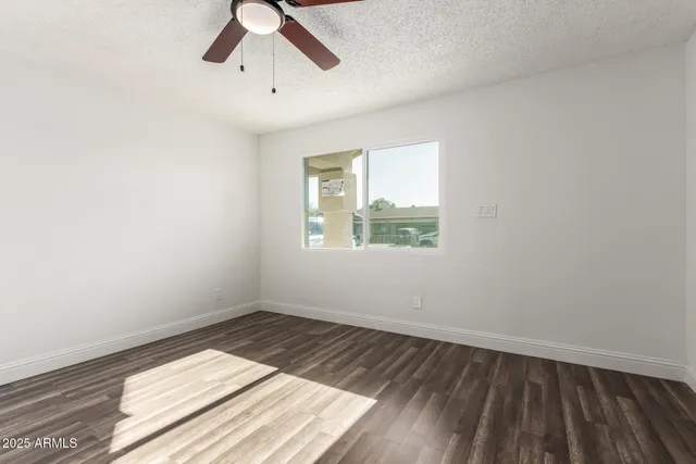 an empty room with wooden floor and a ceiling fan